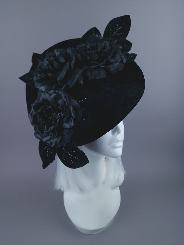 A luxurious black velvet hat base adorned with sculpted black roses and velvet leaves, delicately decorated with black crystals.