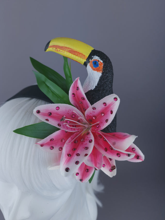 Close up of headpiece glittered toucan, vibrant pink lilies delicately sprinkled with crystals, and sculpted leaf detailing.