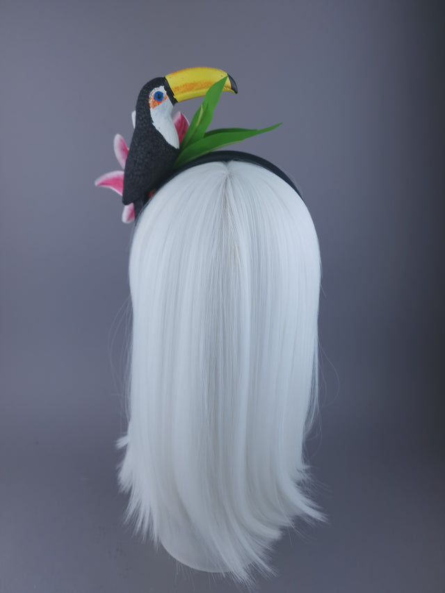 back of headpiece with glittered toucan, vibrant pink lilies delicately sprinkled with crystals, and sculpted leaf detailing.