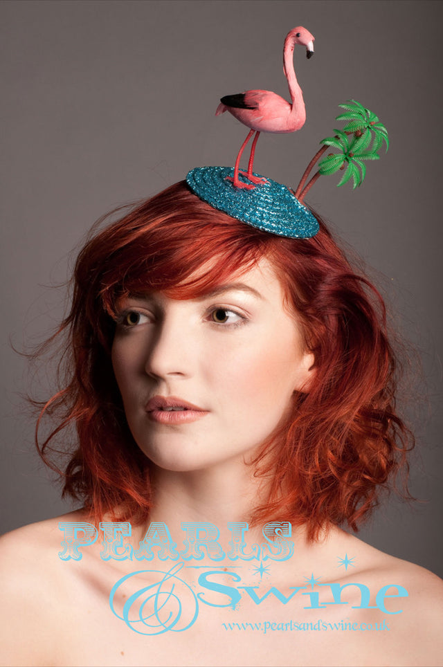 Tropical Flamingo Fascinator "Tropicana" A holiday scene fascinator featuring a pink feathered flamingo, a blue glitter sea and a coconut tree backed with leopard print satin. Attaches to your hair with a comb