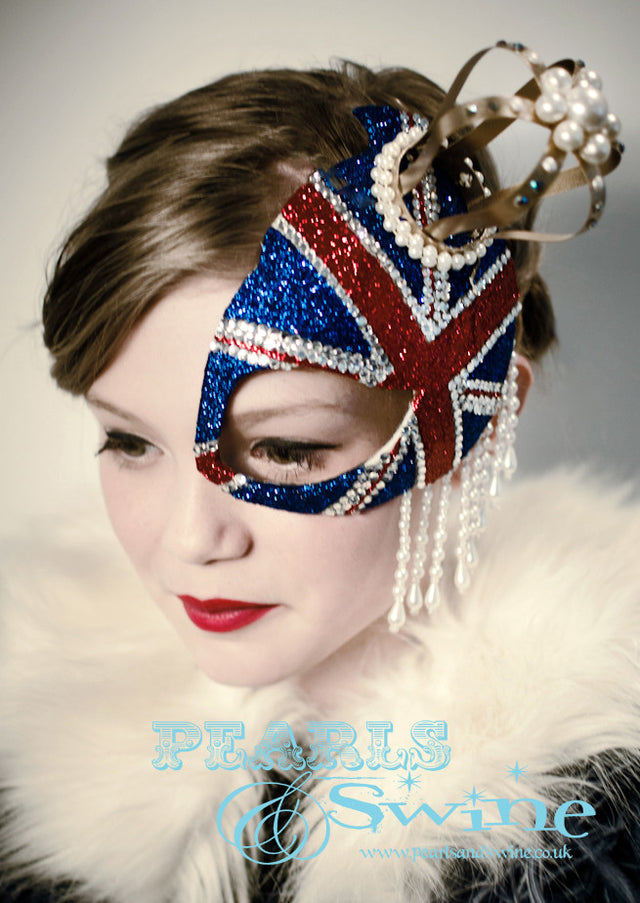 Union Jack Half Mask Fascinator "Regency" This half mask fascinator has a glittered Union Jack with a gold crown decorated in pearls, crystals, and pearl beading. Attaches with a comb.