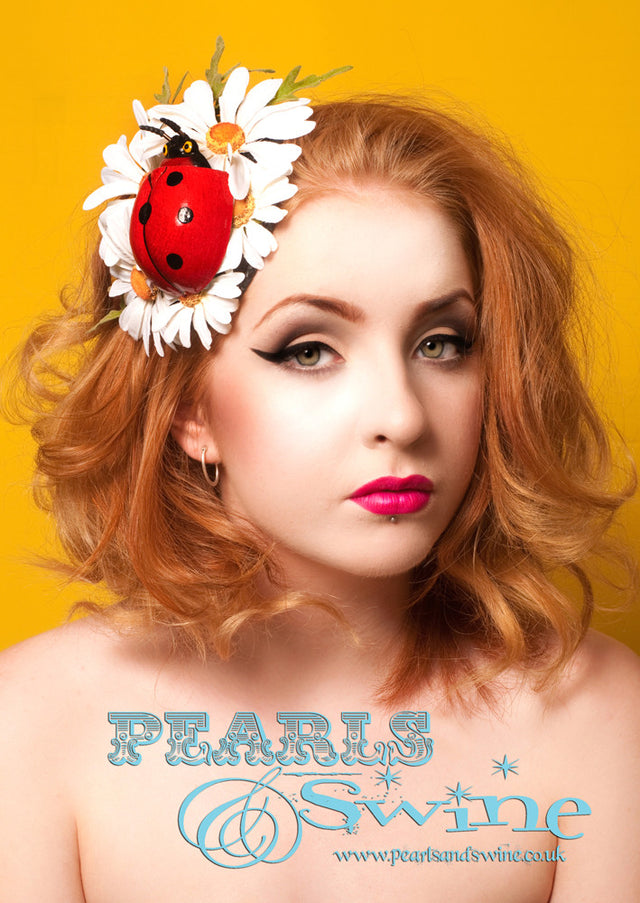A fun, sweet, 1970's Hippie inspired daisy covered fascinator decorated with a giant red ladybird. Attaches with a comb and adjustable hat elastic. This headpiece is ideal for summer and would be gorgeous on a quirky bride.