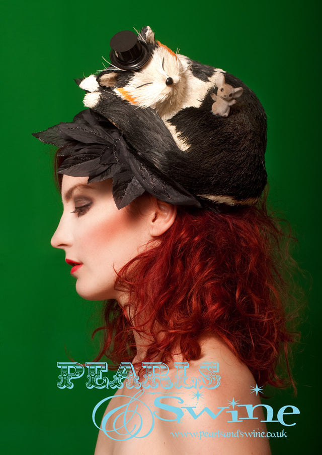 Sleeping Cat Headpiece "Sweet Dreams" Artificial cat, wearing a little top hat. sleeping on a hat decorated with black leaves. There is a cheeky little mouse sat on the snoozing cat. This one of a kind cat hat attaches with a hidden fascinator base that has a comb on it.