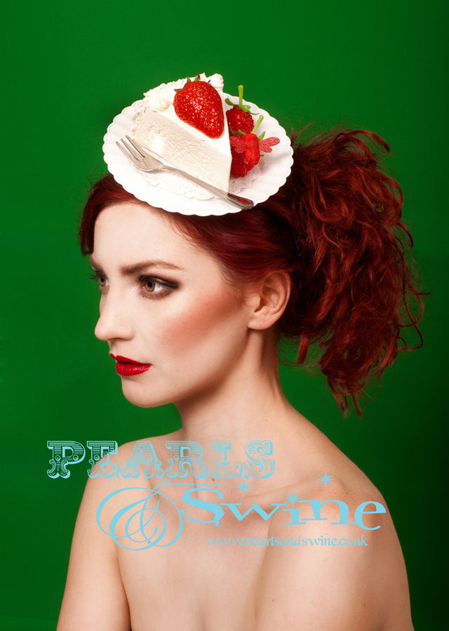 Strawberry Cake Hat "Sweet Tooth" A deliciously realistic slice of cake on a white ornate plate with a silver fork on a hidden fascinator base. Decorated with strawberries and a bee. Attaches with a comb and adjustable hat elastic. Perfectly kitsch headpiece for a tea party or wedding.