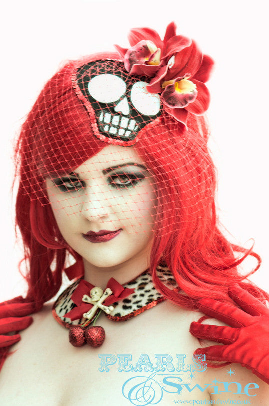 A Mexican Day of the Dead inspired skull fascinator decorated with red orchids, red birdcage veiling and edged in sequins. This Day of the Dead skull fascinator is hand-glittered millinery felt hand blocked to fit against your head in a flattering comfortable way, it s backed with leopard print satin. Attaches with a comb and adjustable hat elastic. Perfect for lovers of skull hats, burlesque hats, and quirky millinery.