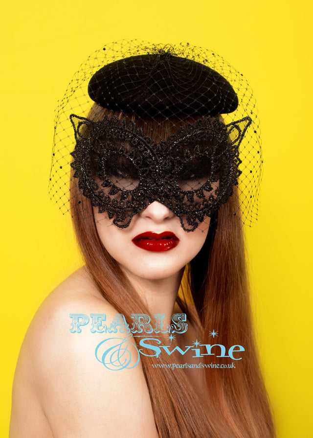 Deliciously decadent black blocked felt hat with a slightly stiffened black lace mask, decorated with black crystals and glitter. This limited edition black veiled mask hat attaches with a comb and adjustable hat elastic. You can position the hat so that the mask fits perfectly in line with your eyes while not pressing against your face. Perfect for Parisian bank robbers, masked balls and generally being mysterious.