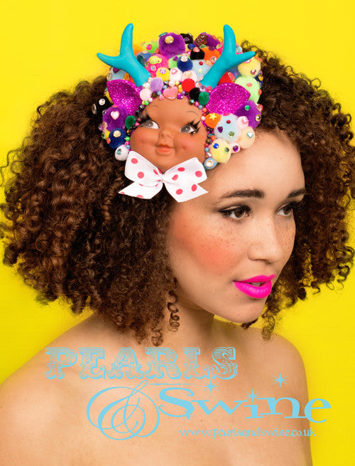 Deer Girl Fascinator "Dolly Dimple" My Deer Girl is a doll-face fascinator decorated with pom poms, pink hand made glittered eats, crystals, beads, and a polka dot bow with hand-made turquoise blue antlers. Attaches with a comb and hat elastic. This is a piece of wearable art that you can hang on the wall when not wearing it.