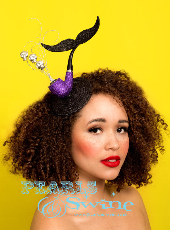 Surreal Pipe Headpiece "El Señor de la Muerte" A fabulously quirky, surreal pipe headpiece set on a fascinator base featuring a sparkling purple pipe with a black glittered moustache, silver glitter smoke, and silver skulls. Attaches with a comb and adjustable hat elastic. This quirky headpiece is part of a collection of pipe headpieces. Inspired by "Ceci n'est pas une pipe" by René Magritte, a Belgian surrealist artist aka "This is not a pipe". Nope, it's a fascinator... Perfect for fans of René Magritt