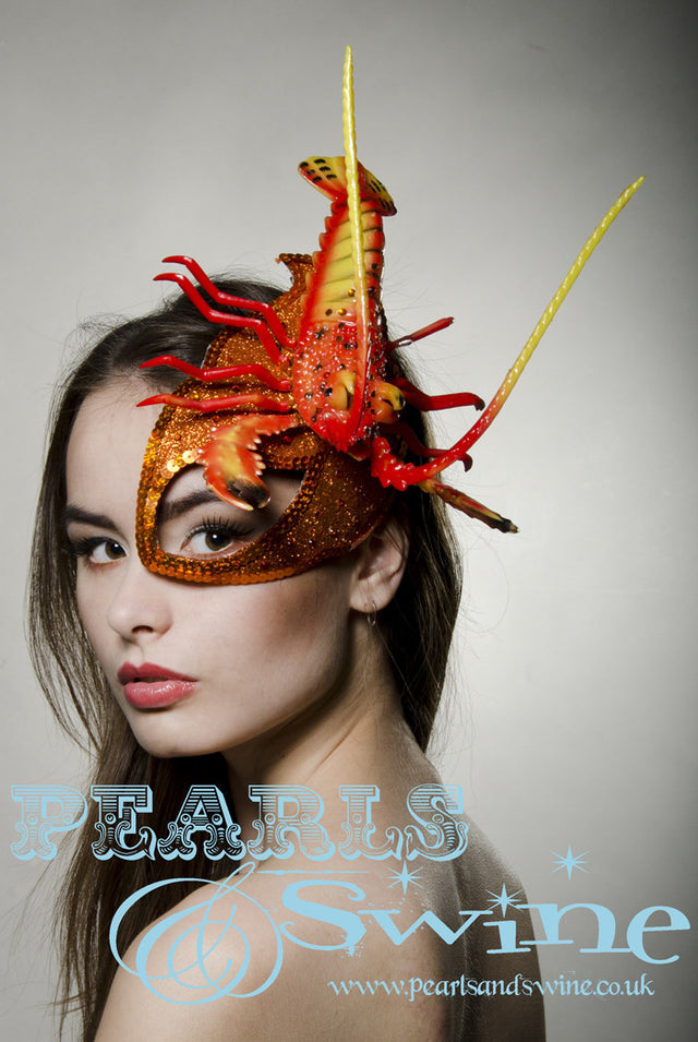 Orange glitter surreal lobster half mask fascinator creation is inspired by Salvador Dali. Made using hand blocked millinery felt backed with leopard print satin fabric, edged with orange sequin and sprinkled with orange crystals. The lobster is sprinkled in orange crystals, the feelers that move when you wear this so you bring the lobster to life. Attaches with a comb, extra bobby pins will help keep firmly in place.