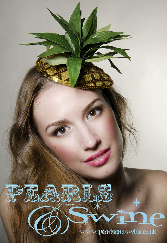 Fabulously kitsch pineapple fascinator decorated with sequins, gold glitter and leaves, backed with leopard print satin, this attaches with a comb and adjustable hat elastic. Perfectly summery headpiece for lovers of retro fruit headpieces.