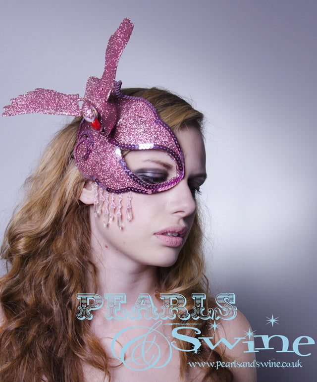 The flamingo half mask fascinator features a candy pink glittered flamingo, set on a hand blocked half mask, edged in pink gems, dripping with pink fringe beading and backed with leopard print satin. Attaches with a comb and adjustable hat elastic.  This half mask fascinator is signature P&S headpiece.  Perfect for a prom, burlesque showgirl or anyone who loves flamingos