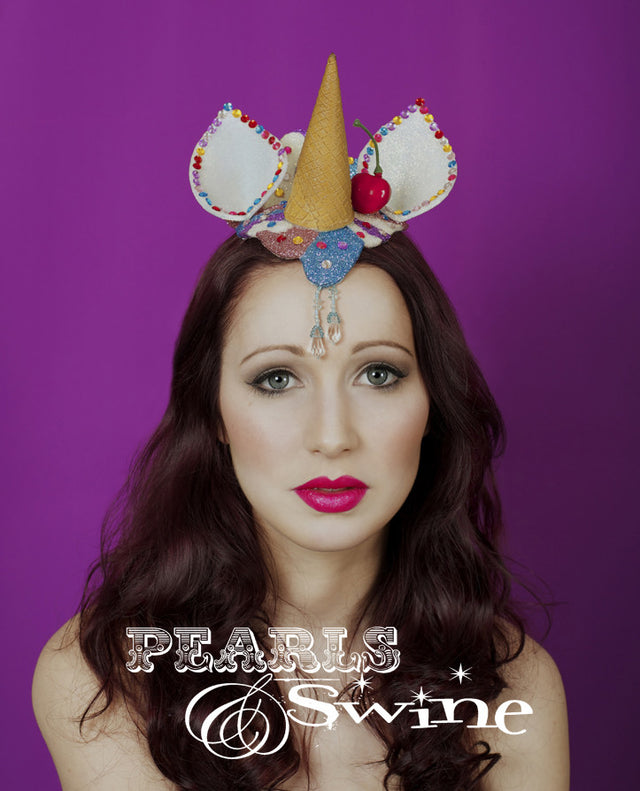 Unicorn Ice Cream fascinator "Sprinkles" This dropped ice cream cone that doubles as a unicorn horn is hand-moulded and glittered in pink, blue, and iridescent white. The ears are decorated with gem"100's & 1000's", and the ice cream cone unicorn horn has a cherry on top. Backed with leopard print satin it attaches with a comb and hat elastic.