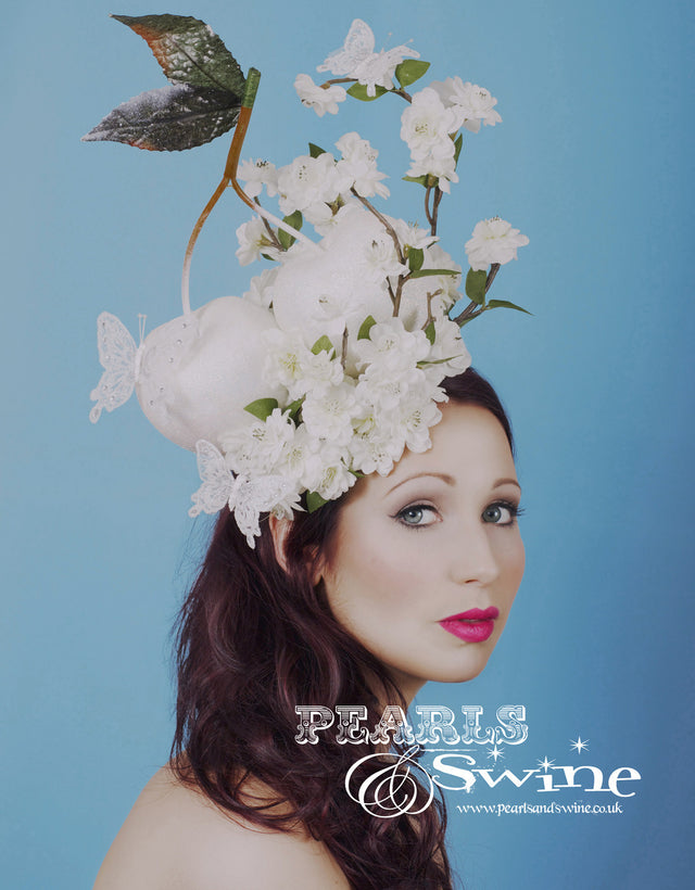 Giant cherries in white glitter, decorated with cherry blossoms and white butterflies set on a white fascinator base. Attaches with a comb and adjustable hat elastic. Should you require extra securing just use bobby pins. This is a one of a kind headpiece. Perfect for a unique bride, Royal Ascot Ladies Day or anyone who loves giant cherries.