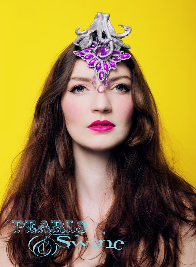 One of a kind surreal metallic silver octopus fascinator on a small silver teardrop shaped base, this can be worn centrally or to either side. It is decorated with purple jewels and fringe beading. Attaches with a comb and adjustable hat elastic. This surreal octopus fascinator is the sort of thing you'd see worn in a science fiction b-movie somehow. Very Barbarella-esque. This is a "Say Something Hat", which demands a second look but isn't too big so perfect for the more demure hat wearer who wants somet