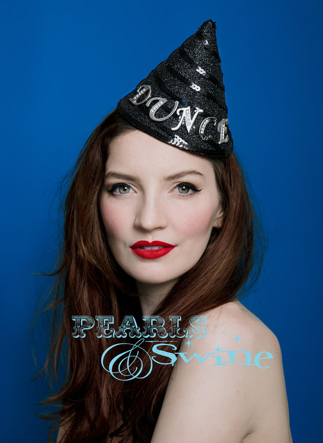 Black glittered Dunce hat fascinator with "Dunce" in diamante lettering is set on a fascinator style base, which is sturdy but lightweight. Attaches with a comb and adjustable hat elastic. This dunce hat fascinator is a bit of fun. I have always wanted to make one. It's inspired by the cone shaped hats used to punish naughty children in Victorian schools.