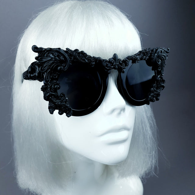 Close up shot of a pair of ornate sunglasses with black filigree design displayed on a mannequin head.