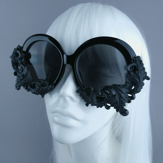 Close up of oversized black round sunglasses decorated with filigree, displayed on a mannequin head