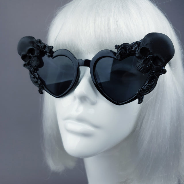 Close-up of hand-decorated, customised, ornate heart-shaped sunglasses with skulls and filigree. Displayed on a mannequin head
