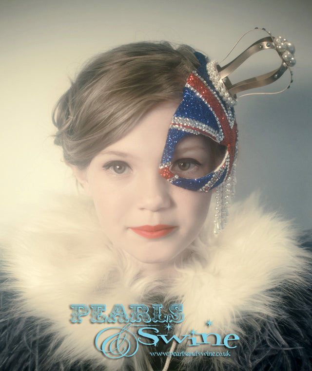 Union Jack Half Mask Fascinator "Regency" This half mask fascinator has a glittered Union Jack with a gold crown decorated in pearls, crystals, and pearl beading. Attaches with a comb.