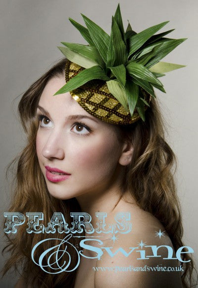 Fabulously kitsch pineapple fascinator decorated with sequins, gold glitter and leaves, backed with leopard print satin, this attaches with a comb and adjustable hat elastic. Perfectly summery headpiece for lovers of retro fruit headpieces.