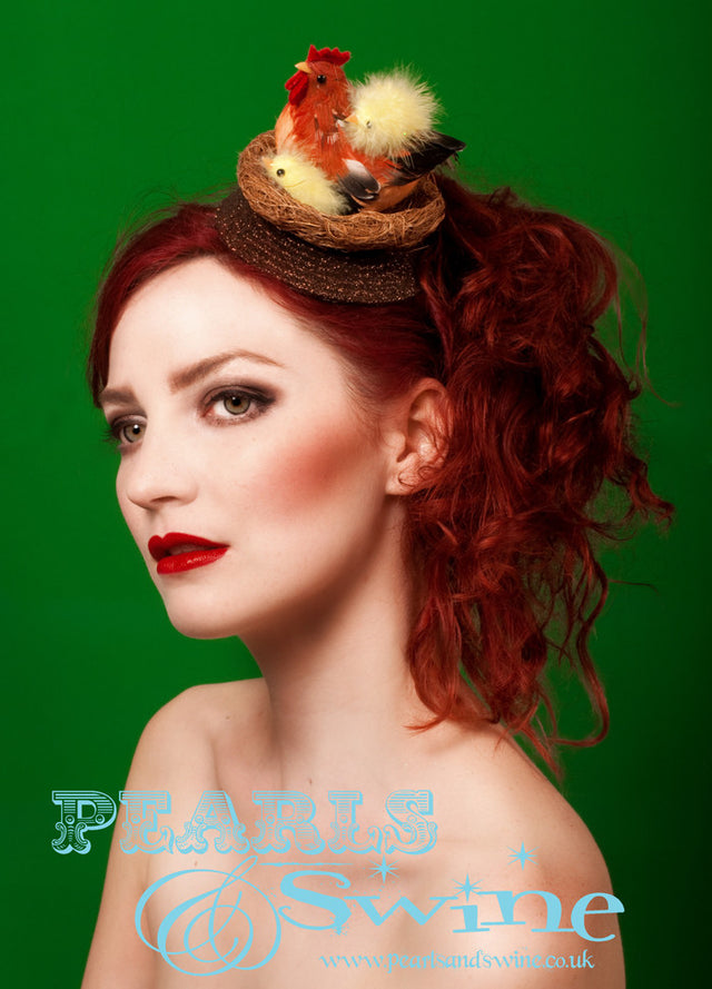 Nest fascinator decorated with a chicken and her fluffy chicks, set on a brown hand glittered base. Backed with a leopard print satin, this attaches with a comb and adjustable hat elastic. This is a cute Easter Bonnet for anyone who loves chickens! 