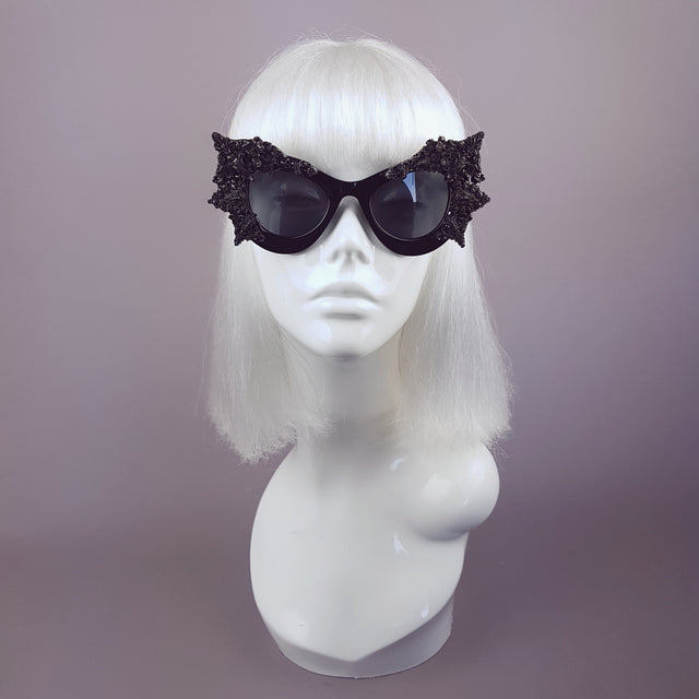 Hand-decorated black filigree ornate sunglasses, displayed on a mannequin head.