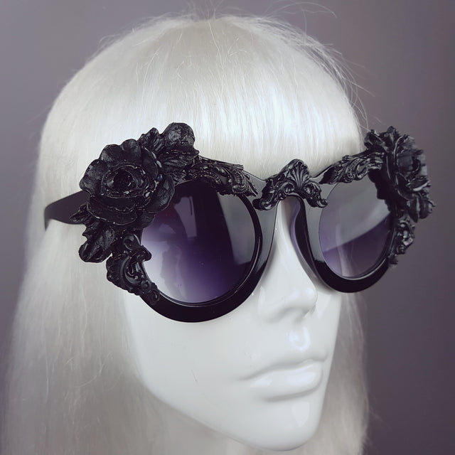 Close-up of customised oversized black sunglasses, with rose and filigree detail. Tinted Lenses.